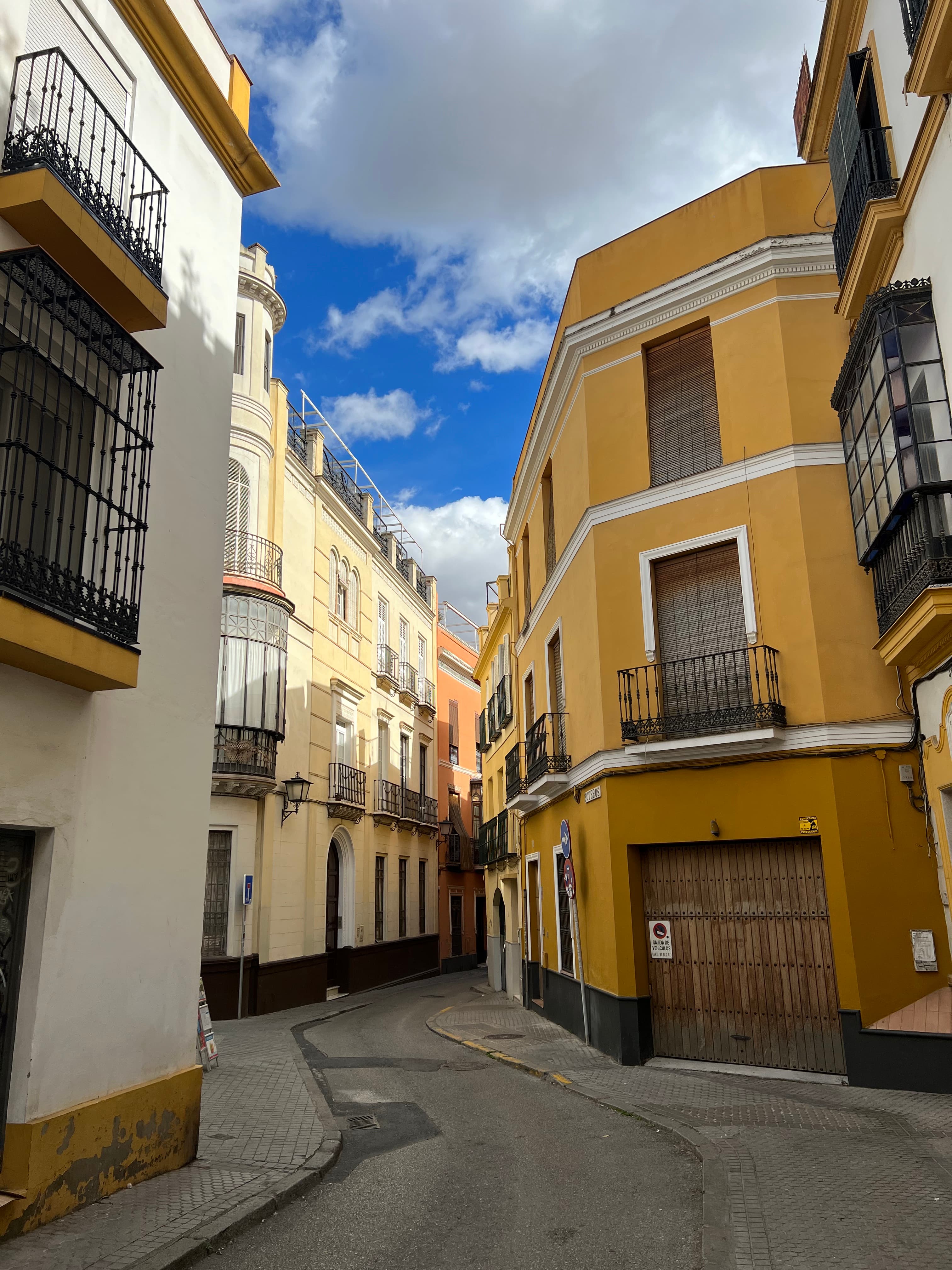 Yellow Andalusian facade with wrought-iron balconies framed against blue sky